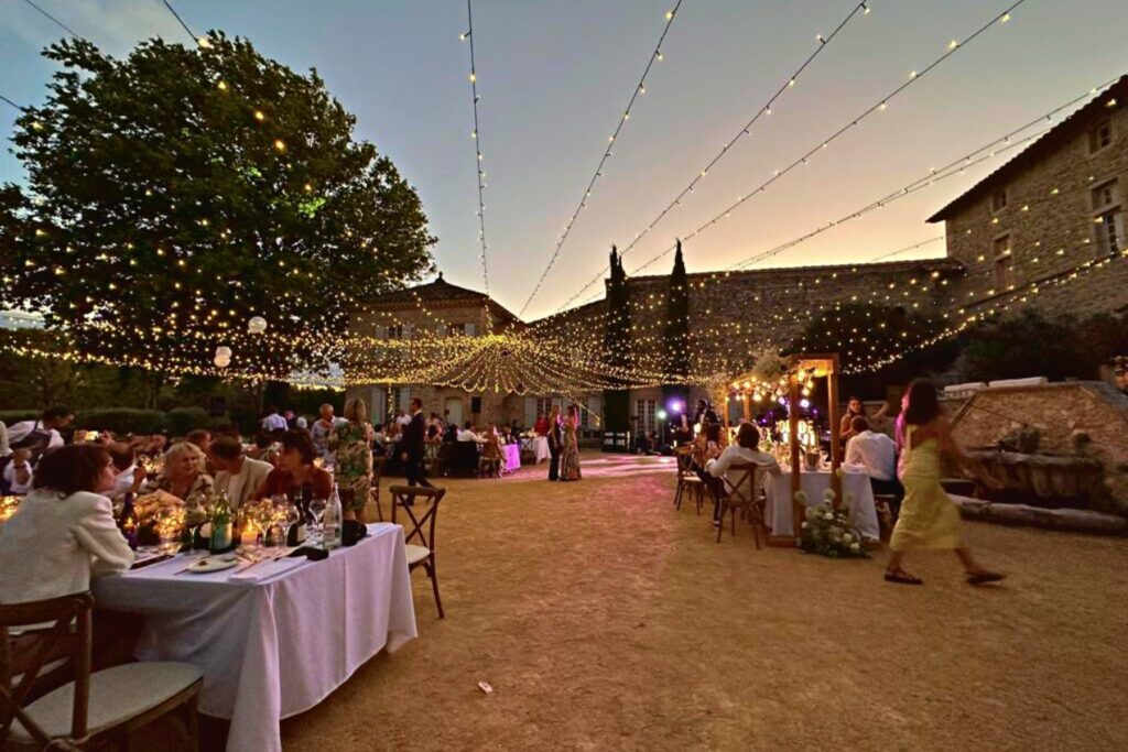 Dîner en plein air le soir, entouré de nos sublimes guirlandes 'ciel étoilé', dans une cour pour un événement.