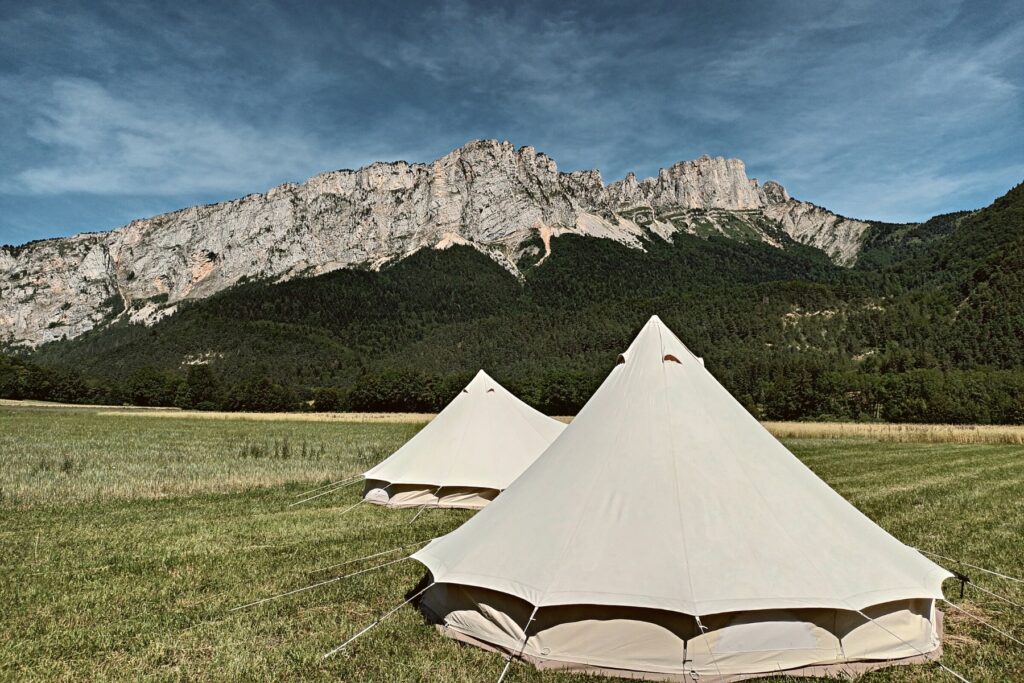 Deux tipis en location dans un champ avec le massif du Vercors en arrière-plan.