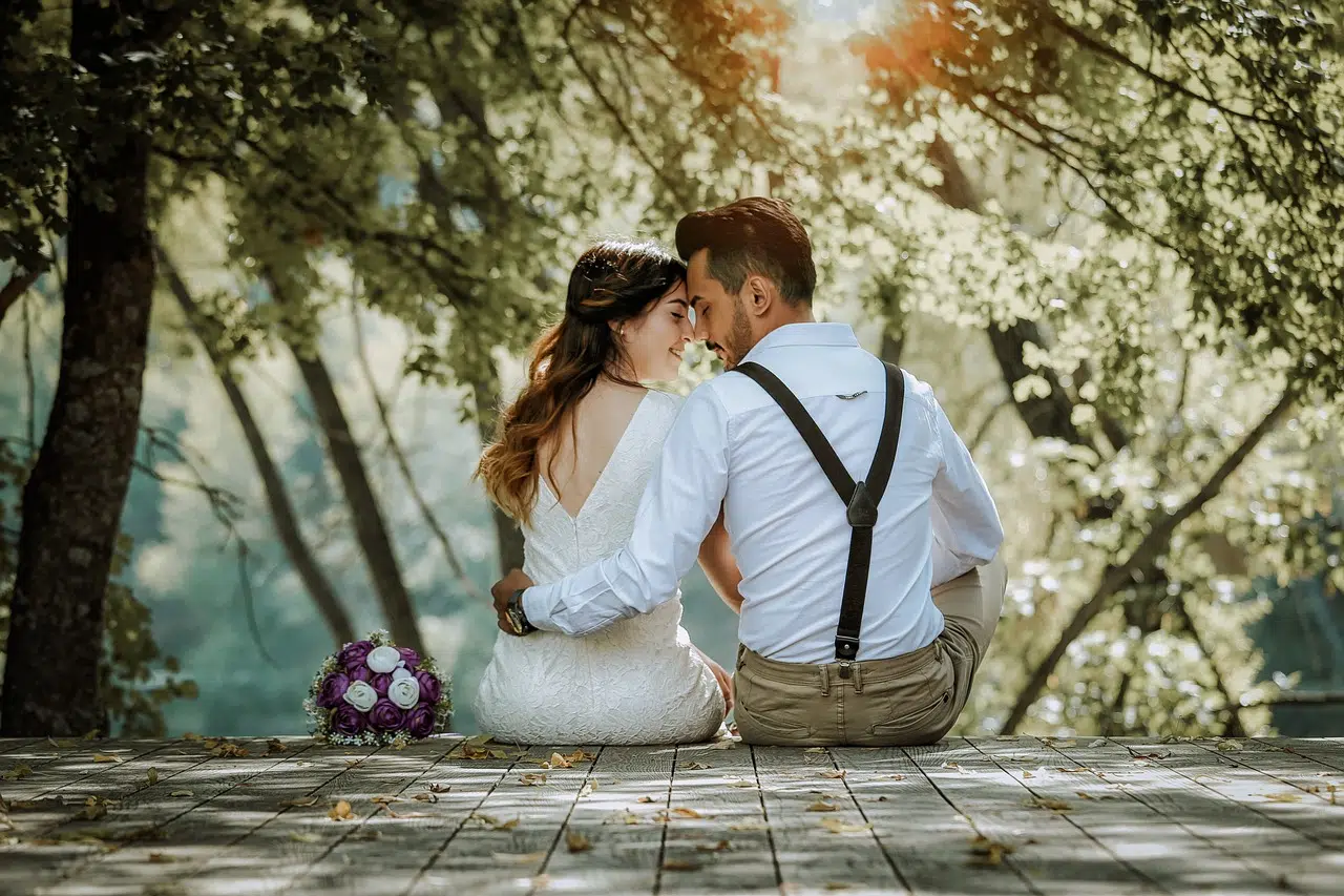 Couple de mariés assis sur une terrasse en bois face à la nature.